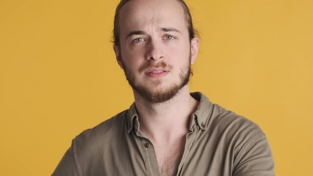 Portrait of young bearded man looking unsure saying yes on camera isolated on yellow background. Agree expression
