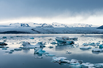 Icebergs in Jokulsarlon glacial lagoon while a snow storm is approaching the area in famous Icelandic travel location