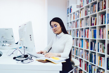 Concentrated female student doing homework in library