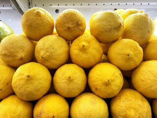 Pile of ripe lemons. Arranged neatly on the supermarket display rack. Fresh Organic Food. Lemon background