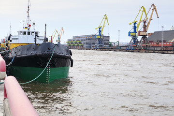 Moored ships in port, on the other shore unloading scrap metal from train wagons with large cranes