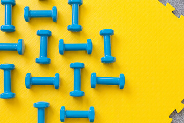 Obraz premium Blue dumbbells on yellow background pattern