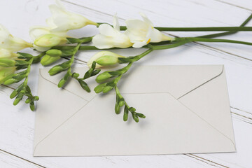 white freesias on an envelope lying on a light background