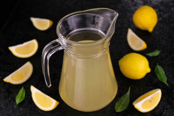A jug of lemon juice on a black background. Top view.