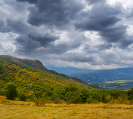 Naklejka premium green mountain valley under a dense cloudy sky