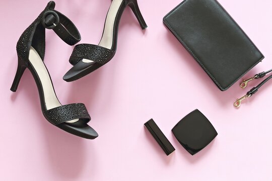 Red sexy silk lingerie, black clatch, perfume bottle and cosmetic products on a pink background. Flat lay, top view trendy beauty female background.