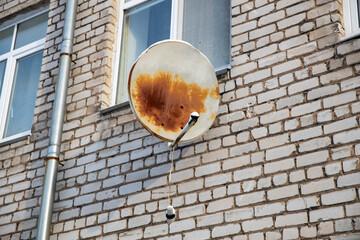 old satellite dish hanging on a brick wall