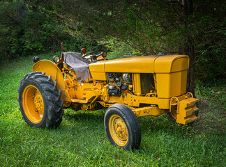 Obraz premium Very old yellow tractor in the yard of my father-in-law's house in Broome County in Upstate NY. What may be an antique tractor still runs and works the fields on this family farm. 