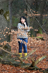 A woman in yellow raincoat and boots wandering in the wood 