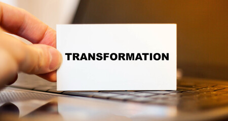 TRANSFORMATION word on a business card in a virtual manager's hand on a computer background