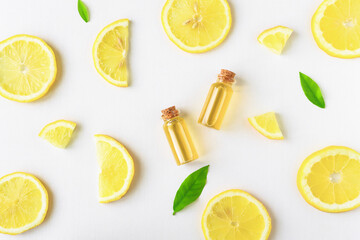 Lemon oil and lemon slices on a light wooden background. Essential oils as an additional treatment and use in aromatherapy.