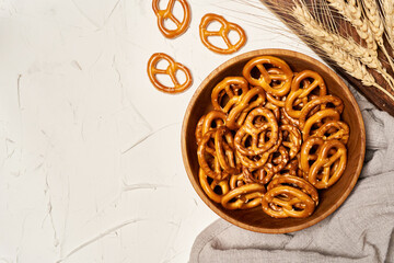 mini salted pretzels in a wooden bowl on white background. hard crackers or snacks. top view, above                                                                           