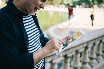 Cropped male tourist tracking gps via location app on modern touch pad using 4g internet connection in city, aged man searching travel information and making online booking on digital tablet