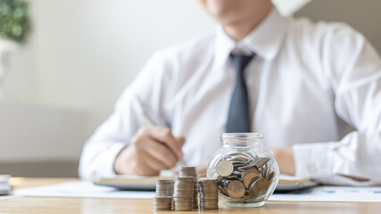 Dollar coins arranged in a slope graph, Blurred image of a businessman pressing a calculator, Financial business growth, Saving money for business growth or long-term profitability, Save money.