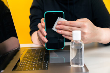 Desinfection concept. Woman desinfecting phone by wet wipe.
