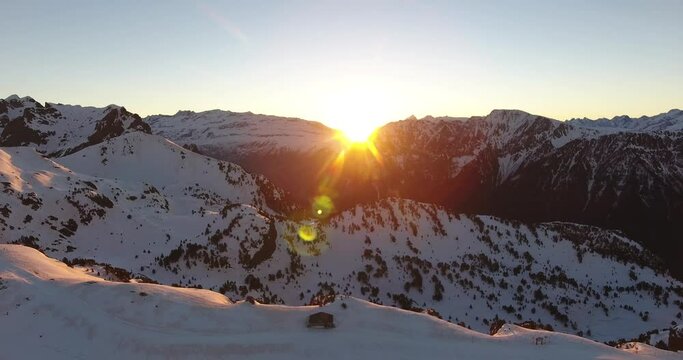 Alps sunrise at Chamrousse peaks in France with bright sun above ridge, Aerial orbit right