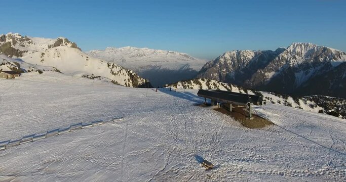 Ski lift station at Chamrousse mountain summit in the French Alps during sunset, Aerial flyover approach shot