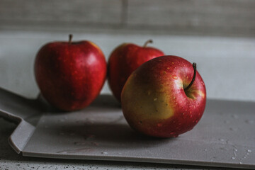 Three red apples on the cutting board