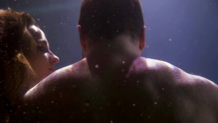 mermaid is stroking body of sunken sailor in sea or ocean, underwater slow motion view