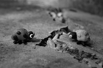 Figurines of two ladybirds made of plasticine. The figures are placed opposite each other. There's a crack between them.