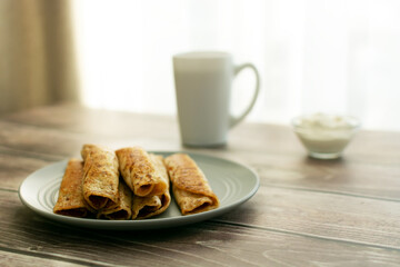 Pancakes on a gray plate, a cup on a wooden table