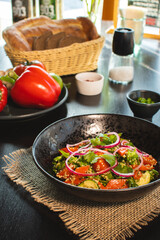 Quinoa salad with tomatoes, avocado, paprika and parsley on black stone plate.