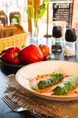 Side view on a dish of eastern european cuisine golubtsy stuffed cabbage leaves with meat or vegetable, with sour cream and carrot.