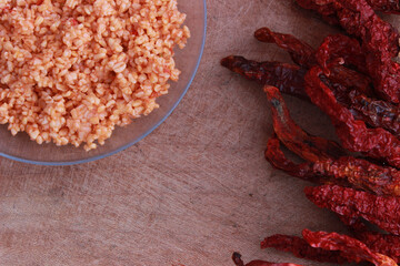 Cracked wheat (bulgur) pilaf with red chilies on wooden table.
