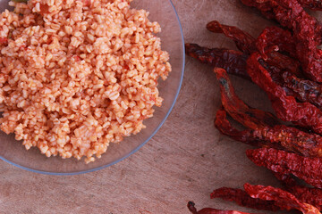 bulgur pilaf (cracked wheat) on wooden table with red chilies 