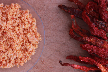 bulgur pilaf (cracked wheat) on wooden table with red chilies 