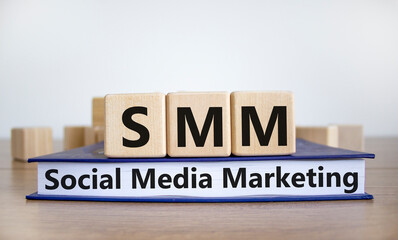 SMM, social media marketing symbol. Wooden cubes on book with word 'SMM - social media marketing' on beautiful white background, copy space. Business, SMM - social media marketing concept.