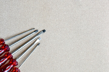 a set of red screw divers lying on a wooden background