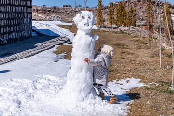 A sweet baby girl playing with a snowman