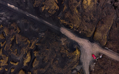 Icelandic road from a drone point of view, top down, with a red car at the end of the road