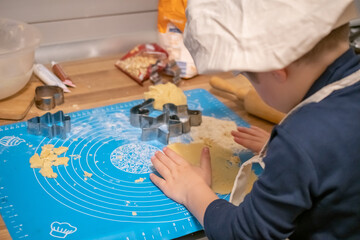 a boy in a chef's cap makes cookies