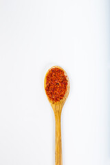 Red chili pepper in wooden spoon on white background.