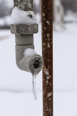 Icicle hanging from tap in early spring, winter