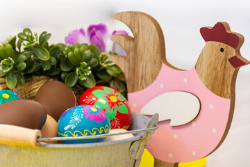 A beautiful Easter decoration with colorful elements such as a wooden chicken, hand-painted Easter eggs and chocolate eggs.