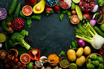 Healthy eating concept: vegetables and fruits on black stone background. Top view. Free space for your text.