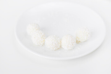 Food photography of natural vegetarian raw food candies with coconut. Close-up white round coconut candy on a white, delicate and airy background. Empty space for text. Flat lay top-down.