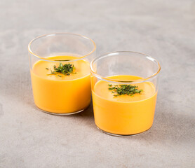 Vegan creamy vegetable jelly carrot with parsley on a plate in a glass on a light background