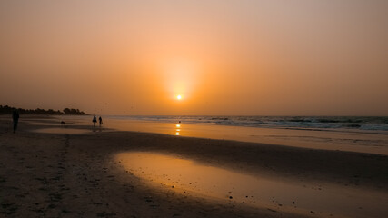 Naklejka premium African beach orange sunset. People / community get together at the evening time. Kotu beach, The Gambia