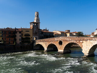 Obraz premium The Ponte di Pietra (Stone Bridge), is the oldest bridge in Verona, is a Roman arch bridge that crosses the Adige River. Under the bridge, the water bumps on the rocks.