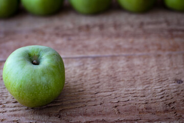 Green apples stand on a wooden surface