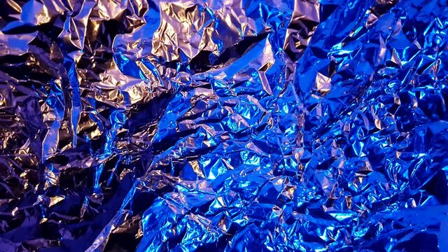 Abstract golden yellow and blue aluminum wrinkled foil background texture reflecting golden yellow and blue light