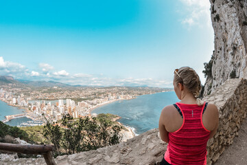 Blonde woman watching city landscape from the mountain. Calpe, Costa Blanca, Spain.