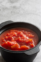 Chopped tomatoes cooked in a cast iron pot.  On a concrete background
