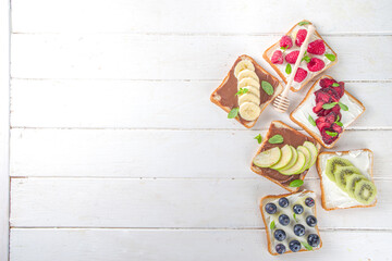 Healthy fruit and berry sandwiches. Tasty diet toast bread with cream cheese and banana, apple, raspberry, blueberry, strawberry, top view copy space