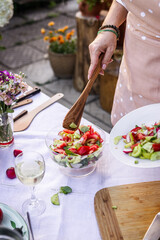Woman serving fresh vegetable salad outdoors. Healthy vegetarian food on banquet and garden party