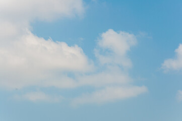 White clouds on blue sky. Nature background. Sunny summer sfternoon. Grained photo